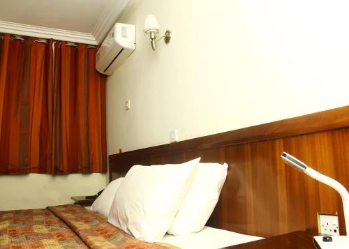 a hotel room with a bed with white pillows at Stadium Hotel in Kumasi