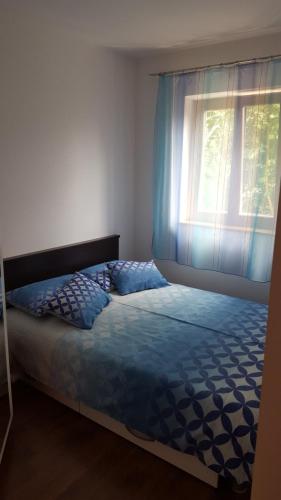 a bedroom with a bed and a window with blue curtains at Apartman Pobri in Opatija