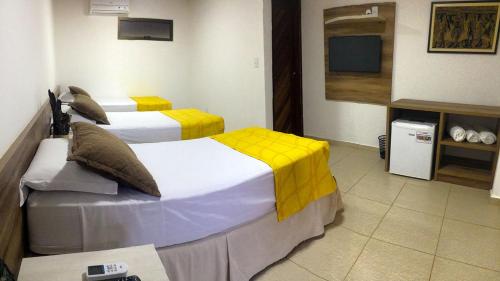 a hotel room with two beds and a television at Pousada Aconchego in Pitimbu