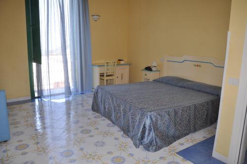 プローチダにあるHotel Savoiaのベッドルーム1室(ベッド1台、テーブル、窓付)