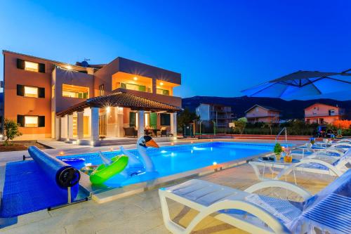 uma piscina com espreguiçadeiras e uma casa em Villa Rusula em Kaštel Novi