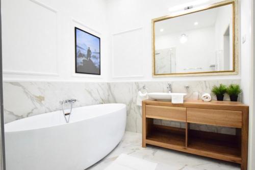 a white bathroom with a tub and a mirror at Luxury Apartment by Hi5 - Szervita Suite in Budapest