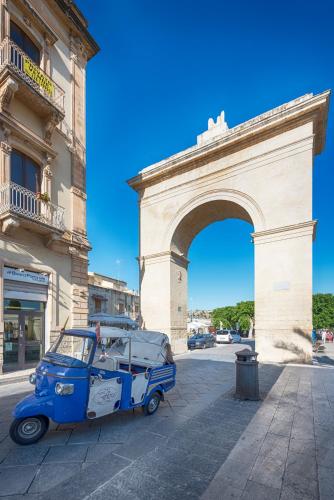 a small car parked in front of a building with an arch at Hotel Flora in Noto