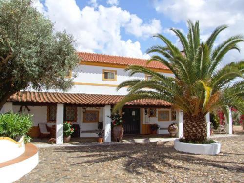 a house with two palm trees in front of it at Monte dos Aroeirais in Fronteira