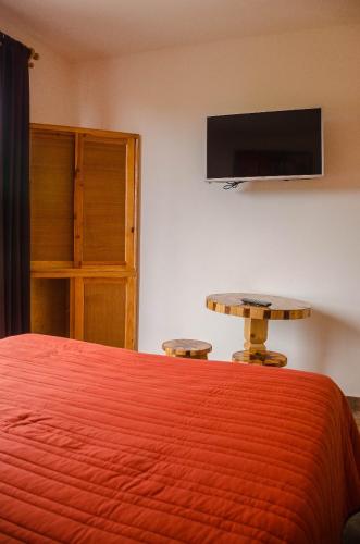 a bedroom with a bed and a table and a tv at Hospedaje Casa Verde in Tepoztlán