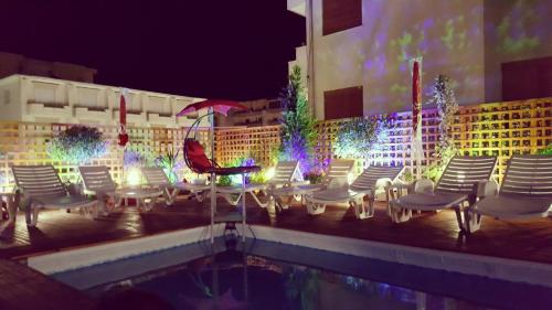 a group of chairs and a swimming pool at night at Sunrise Hotel Cameria in Durrës