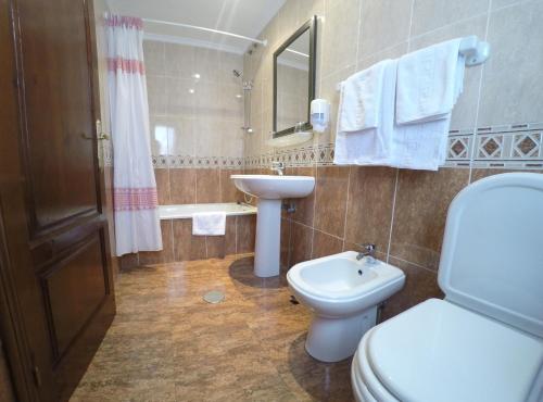 a bathroom with a white toilet and a sink at Hotel Alonso in Llanes