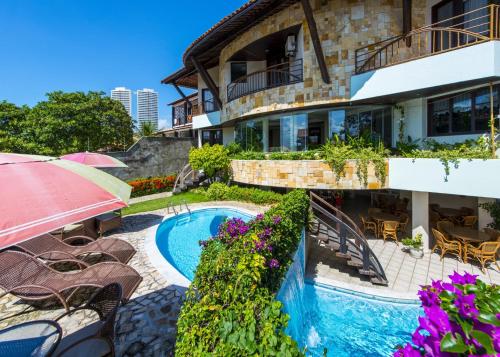 uma casa com uma piscina e cadeiras e um guarda-sol em Divi-Divi Praia Hotel em Natal