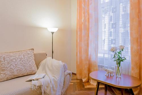 a room with a couch and a table with a vase of flowers at Apartment on Pushkinskaya 17 in Saint Petersburg