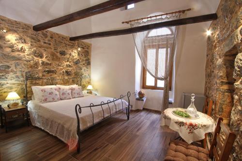 a bedroom with a bed and a stone wall at Schinos Apartments in Mesta