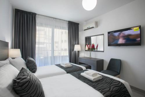 a hotel room with two beds and a flat screen tv at Blazer Residence in Larnaca