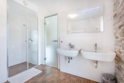 a white bathroom with two sinks and a shower at Apartments Domovoj in Medvode