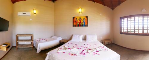 a bedroom with two beds and a tv and a window at Pousada Vento do Kite in Barra Grande
