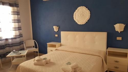 1 dormitorio con cama blanca y pared azul en Demetra Malophoros en Marinella di Selinunte