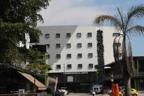 a white building with a palm tree in front of it at Homesuites Malecon in Culiacán