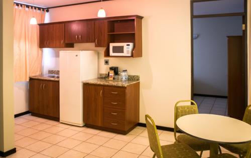 a small kitchen with a table and a refrigerator at Hotel y Restaurante El Guarco in Cartago