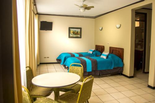 a bedroom with a bed and a table and chairs at Hotel y Restaurante El Guarco in Cartago