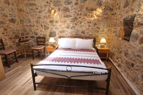 a bedroom with a bed in a room with stone walls at Schinos Apartments in Mesta