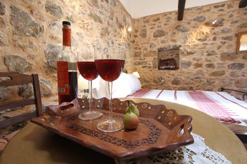 two glasses of wine on a wooden tray with a bed at Schinos Apartments in Mesta