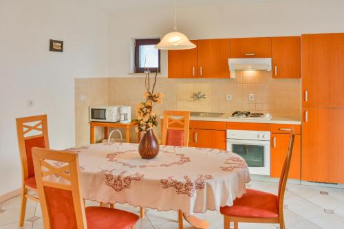 a kitchen with a table with a vase of flowers on it at Apartments Dada in Senj