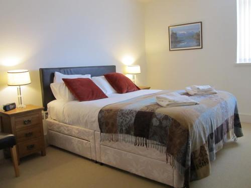 a bedroom with a large bed with red pillows at Bridge Street Apartments in Inverness