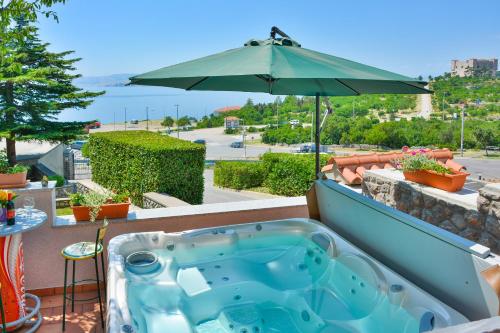 a hot tub on a balcony with an umbrella at Apartments Dada in Senj