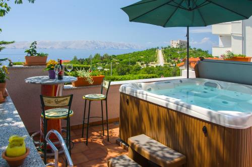 a hot tub on a balcony with an umbrella at Apartments Dada in Senj