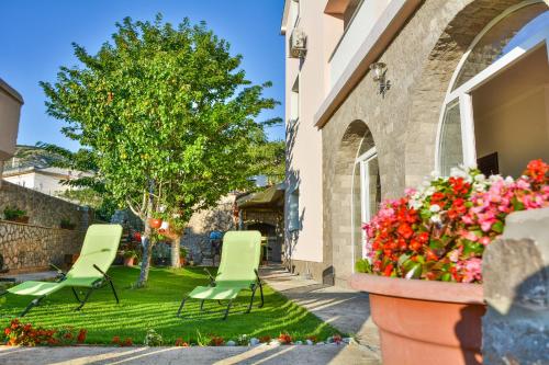 two chairs and a tree in a yard with flowers at Apartments Dada in Senj