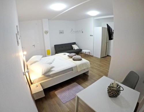 a white bedroom with a bed and a table at Guesthouse Villa DomeNico in Lozovac