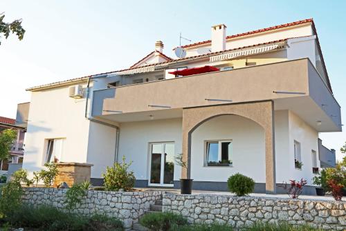 a white house with a stone wall at Guesthouse Villa DomeNico in Lozovac