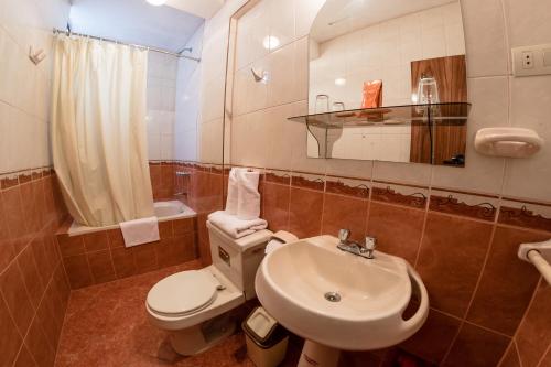 y baño con aseo blanco y lavamanos. en Hotel T'ika en Puno