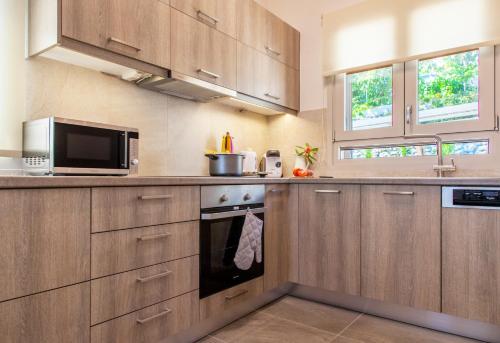 a kitchen with wooden cabinets and a microwave at Karya Villas in Kariá