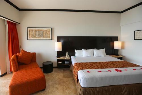 a hotel room with two beds and a chair at Azul Ixtapa All Inclusive Resort in Ixtapa
