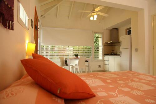 a bedroom with a bed with an orange pillow and a kitchen at Complejo las Morochas in Valeria del Mar