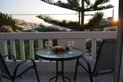 a table with two glasses of wine and a bowl of fruit at Thegaia Studios in Rethymno Town