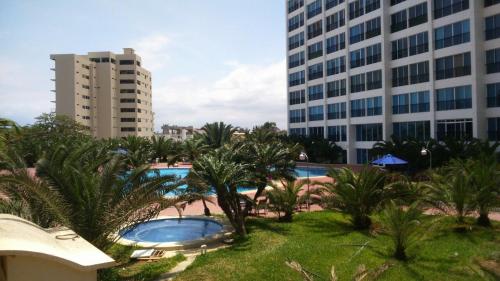 vistas a una piscina con palmeras y edificios en Punta Centinela Apartment en Punta Blanca