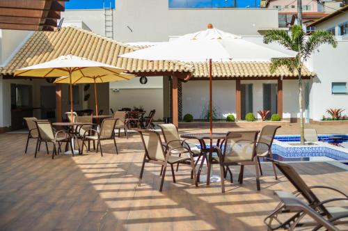 an outdoor patio with tables and chairs and umbrellas at Hotel Chapadao Da Canastra in São Roque de Minas