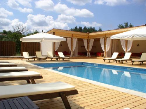 a swimming pool with lounge chairs and umbrellas at Hotel Par Avion in Apriltsi