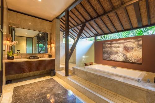a bathroom with a large tub and a large mirror at Villa Air Bali Boutique Resort and Spa in Seminyak