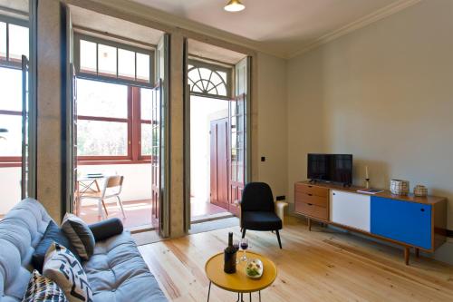 ein Wohnzimmer mit einem blauen Sofa und einem Fernseher in der Unterkunft Trait House in Porto