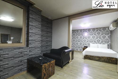 a bedroom with a bed and a chair and a mirror at Hotel Lie in Geoje 