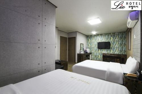 a hotel room with two beds and a tv at Hotel Lie in Geoje 