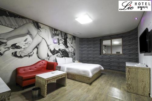 a hotel room with a bed and a red chair at Hotel Lie in Geoje 