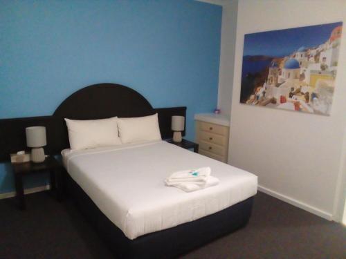 a bedroom with a bed and a blue wall at Blue Pacific Swansea in Swansea