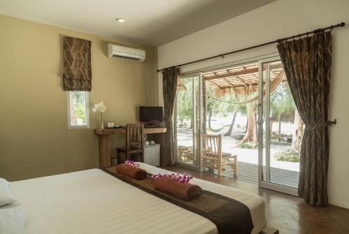 a bedroom with a bed and a sliding glass door at Angkana Bungalows adults only in Thongsala