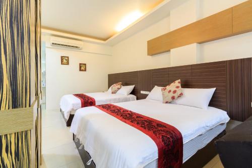 two beds in a hotel room with white sheets at 水和風民宿 in Dongshan