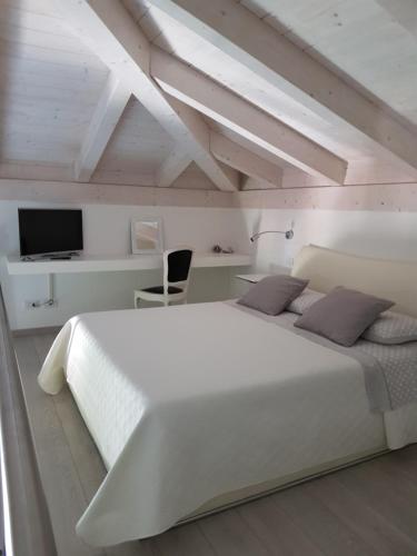 a bedroom with a large white bed and a tv at Agriturismo La Torretta in Pescantina