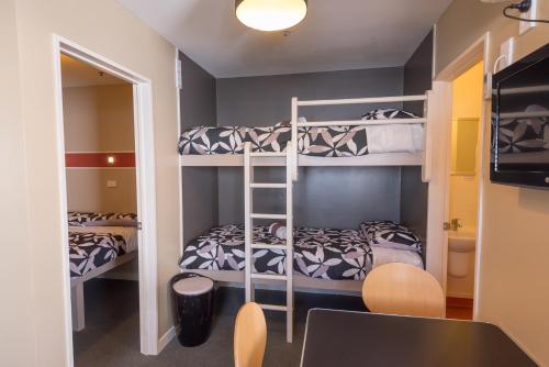 a room with two bunk beds and a desk at Astray Motel in Rotorua