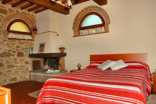sypialnia z łóżkiem i kominkiem z 2 oknami w obiekcie Agriturismo La Marginella w mieście Pescia