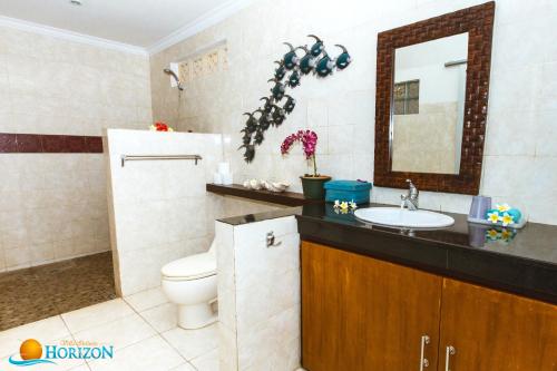 a bathroom with a toilet and a sink and a mirror at Villa Infinite Horizon in Amed